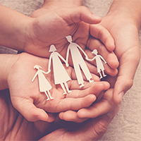 Adult and children hands holding paper family cutout, family hom